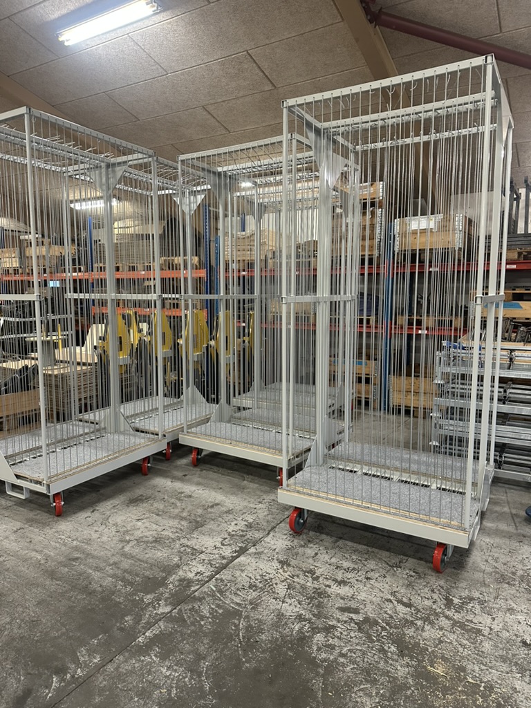Hohe Produktionswagen mit Gitterwänden in einer Werkstatt